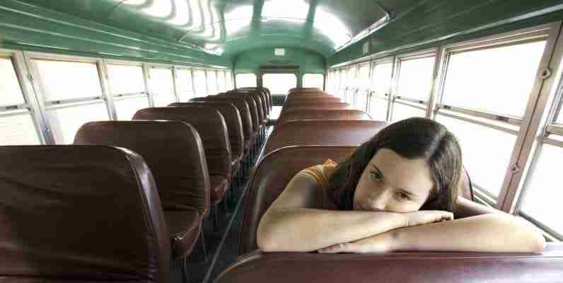 Teen sitting on a school bus.