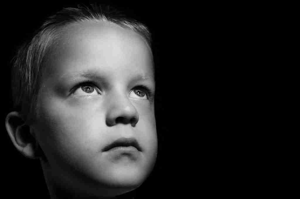 Pathological demand avoidance in children: Young boy's face in black and white, looking up.