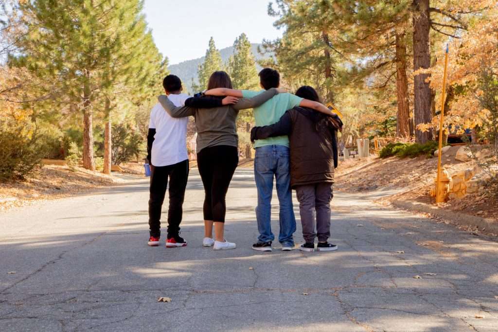 Teens and family members stand with arms around each other. treatment for teen attachment issues, programs for at-risk youth
