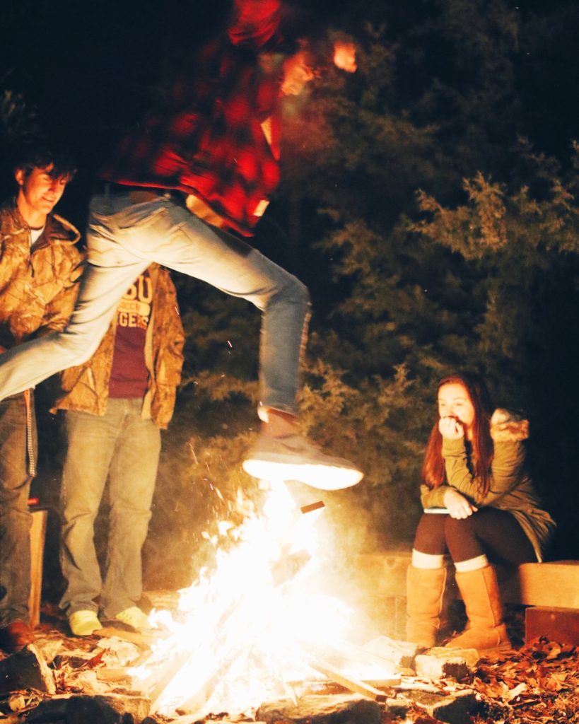 Teen boy jumps over a fire because of peer pressure at a high school party.
