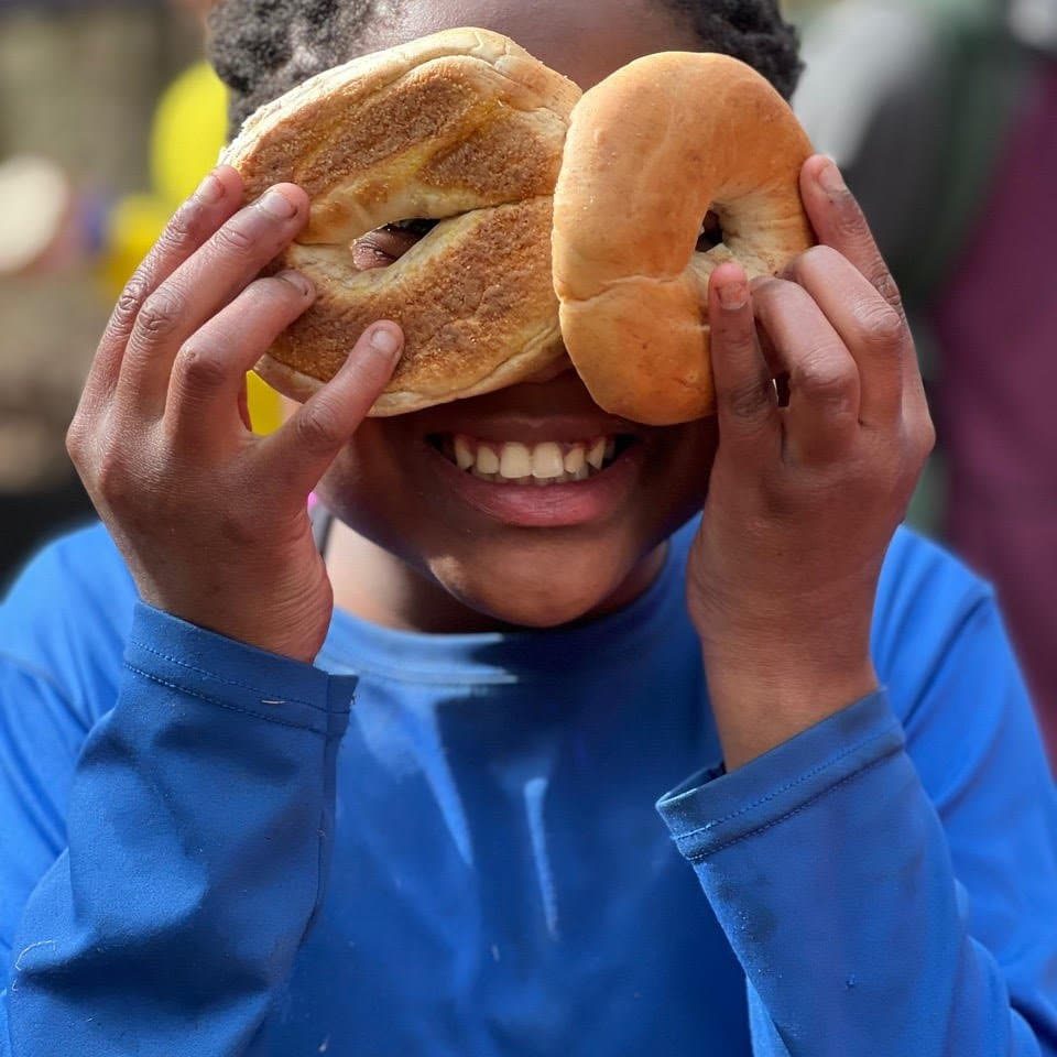 Child holds up two bagels.